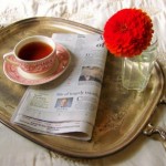 Romantic breakfast tray with tea, newspaper and flower